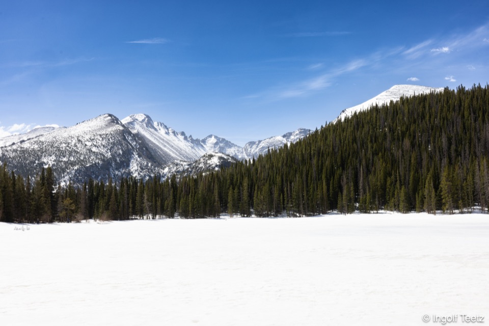 Schneebedeckter Bergsee vor verschneiten Gipfeln der Rocky Mountains